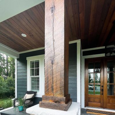 A Wooden Pillar Is Neatly Polished In Brown, It Is Outside Of A House Colored Brown From All The Wooden Parts