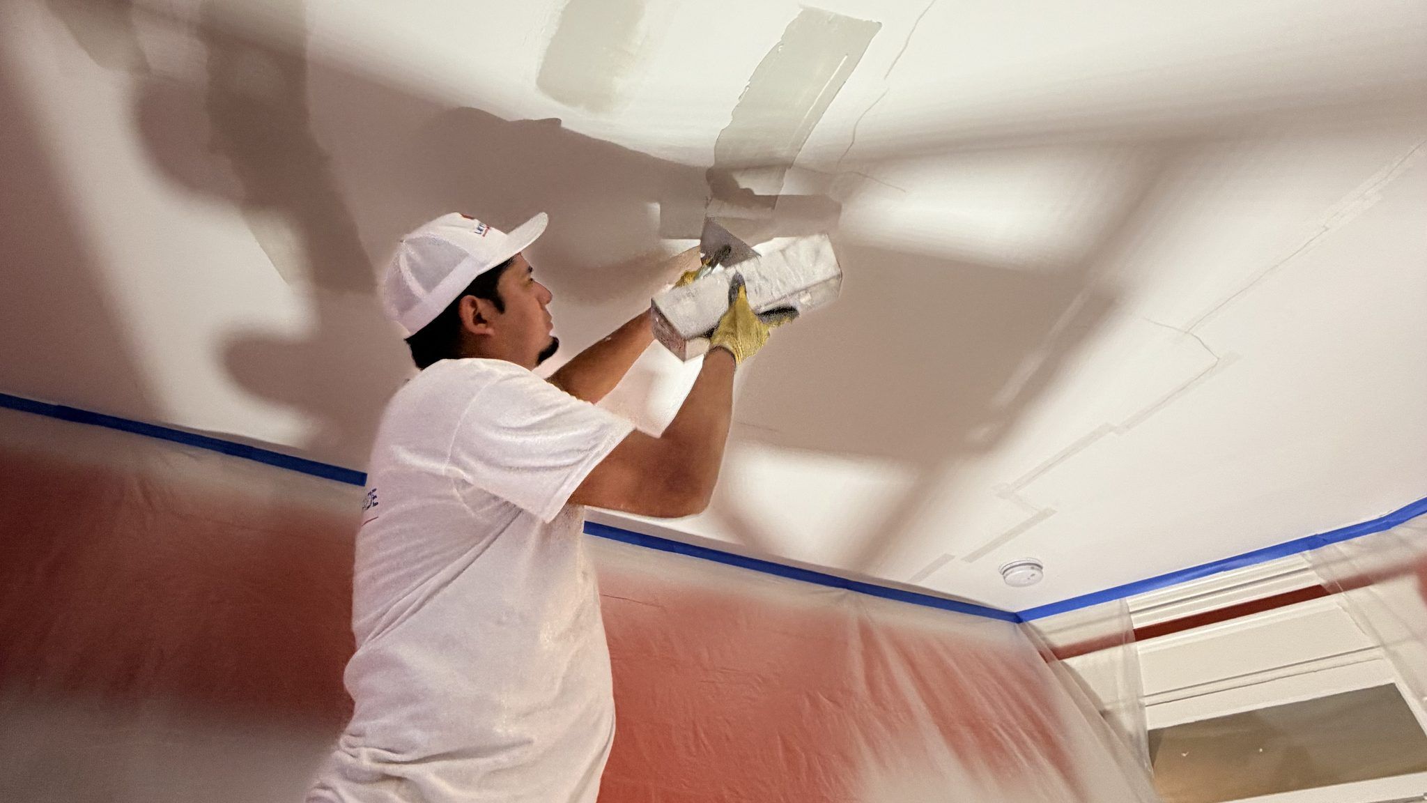 Painter Skim Coating A Ceiling During Drywall Repair