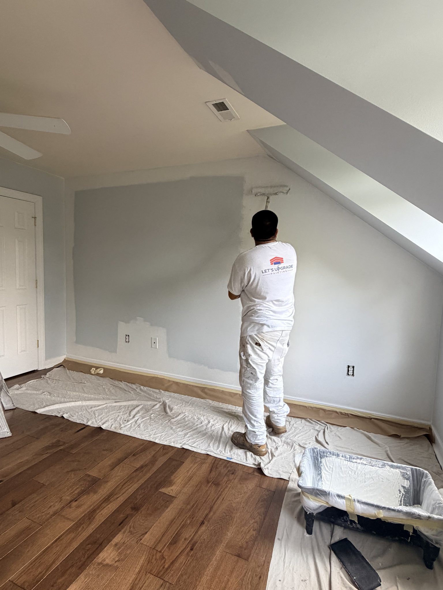 Painter Rolling A Wall Under A Sloped Ceiling