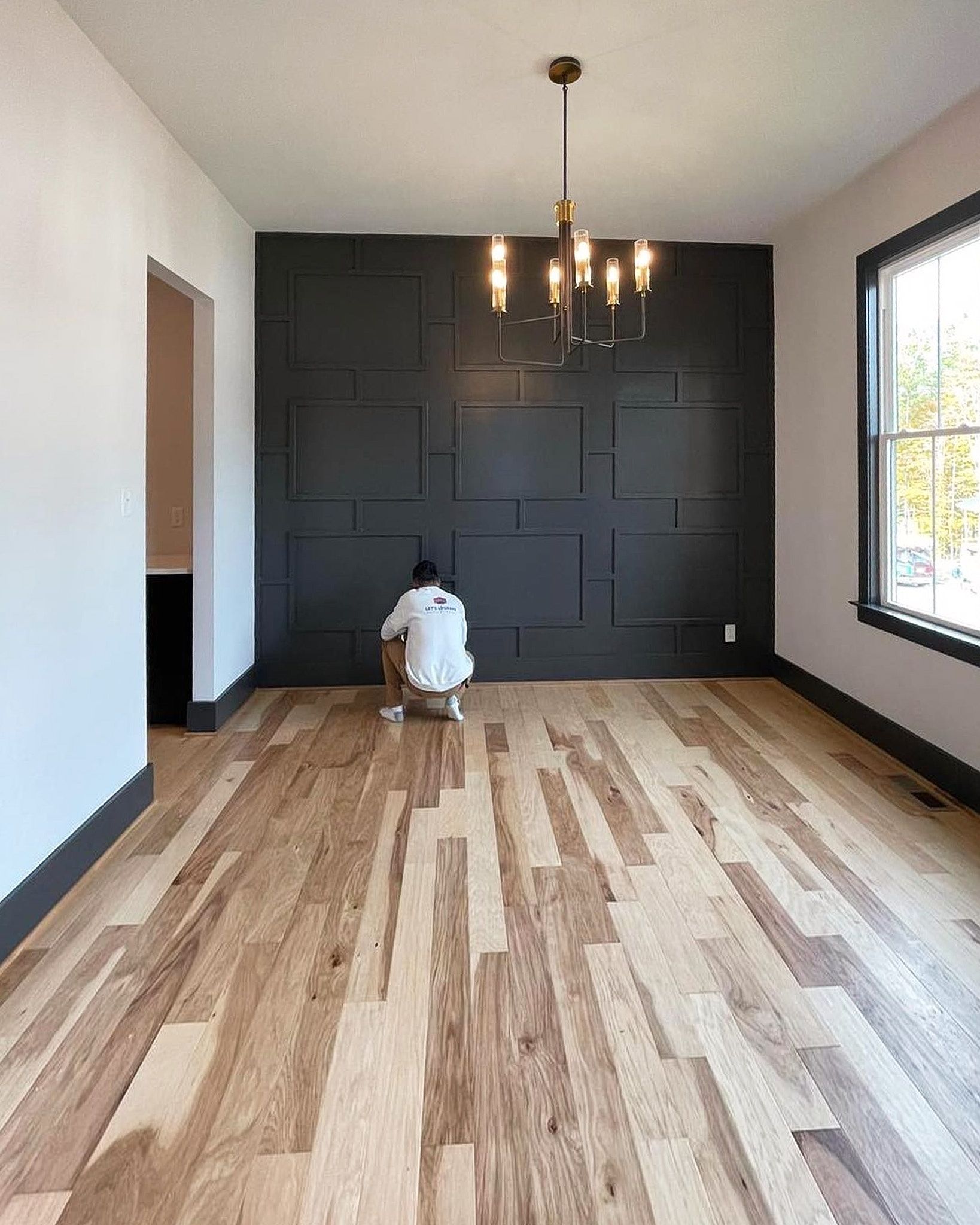 The Painter Is Working On The Feature Wall Inside The Room With Jet Black Color Having Some Raised Box Patterns On It