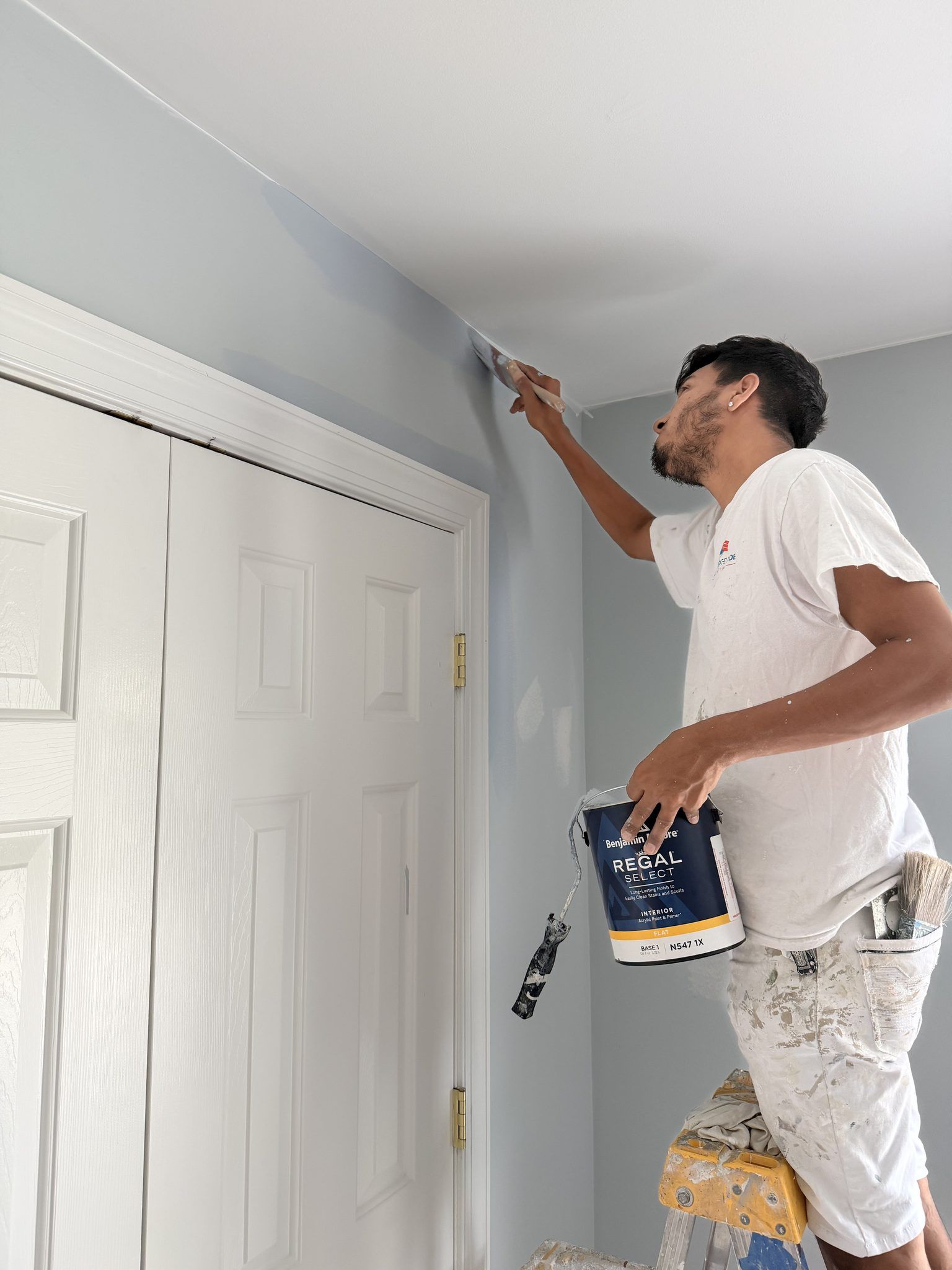 Painter Cutting In A Ceiling Line By A Closet