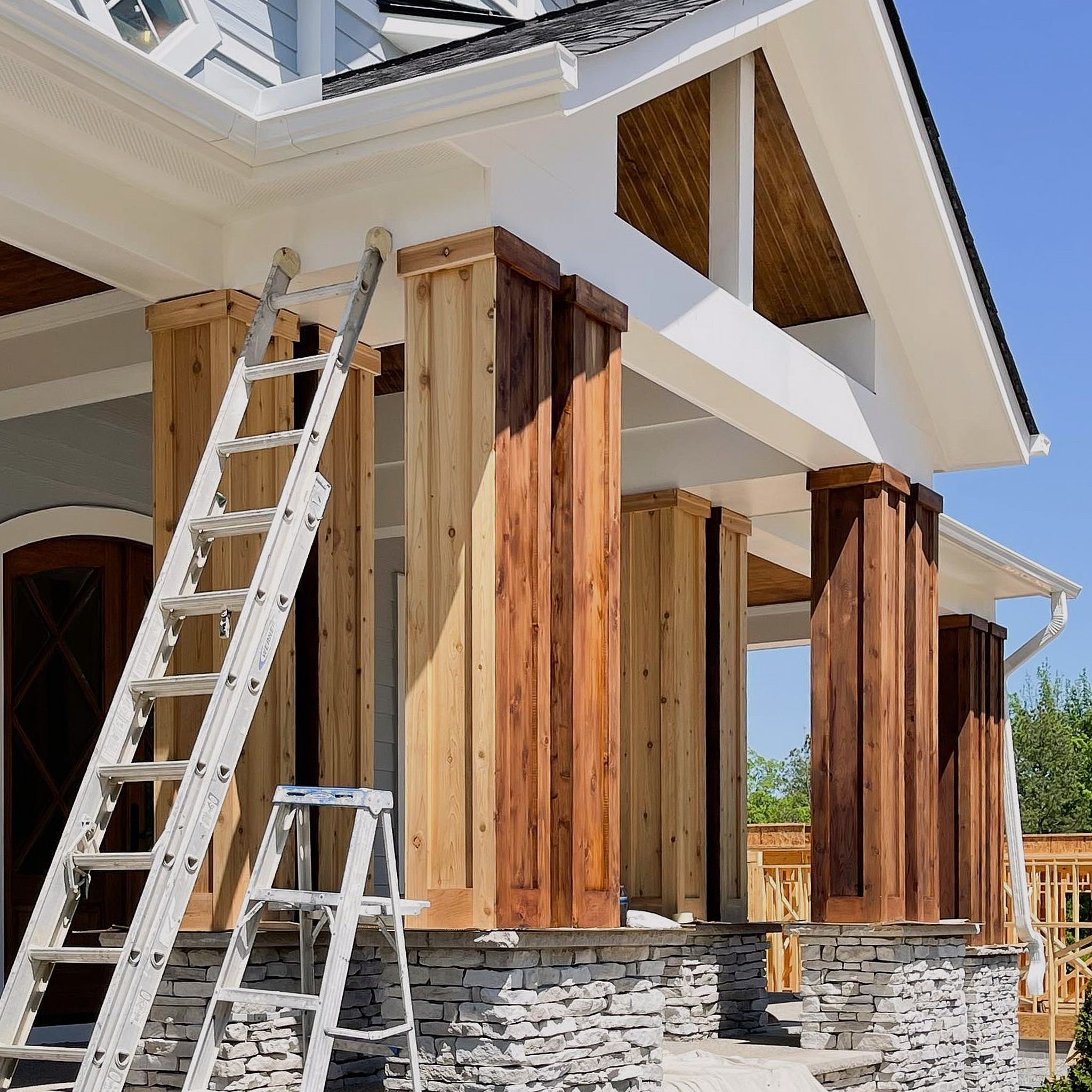 Beautiful House Painted In White With A Dark Roof, Featuring Beautiful Wooden Pillars In A Brownish Color For Beautification