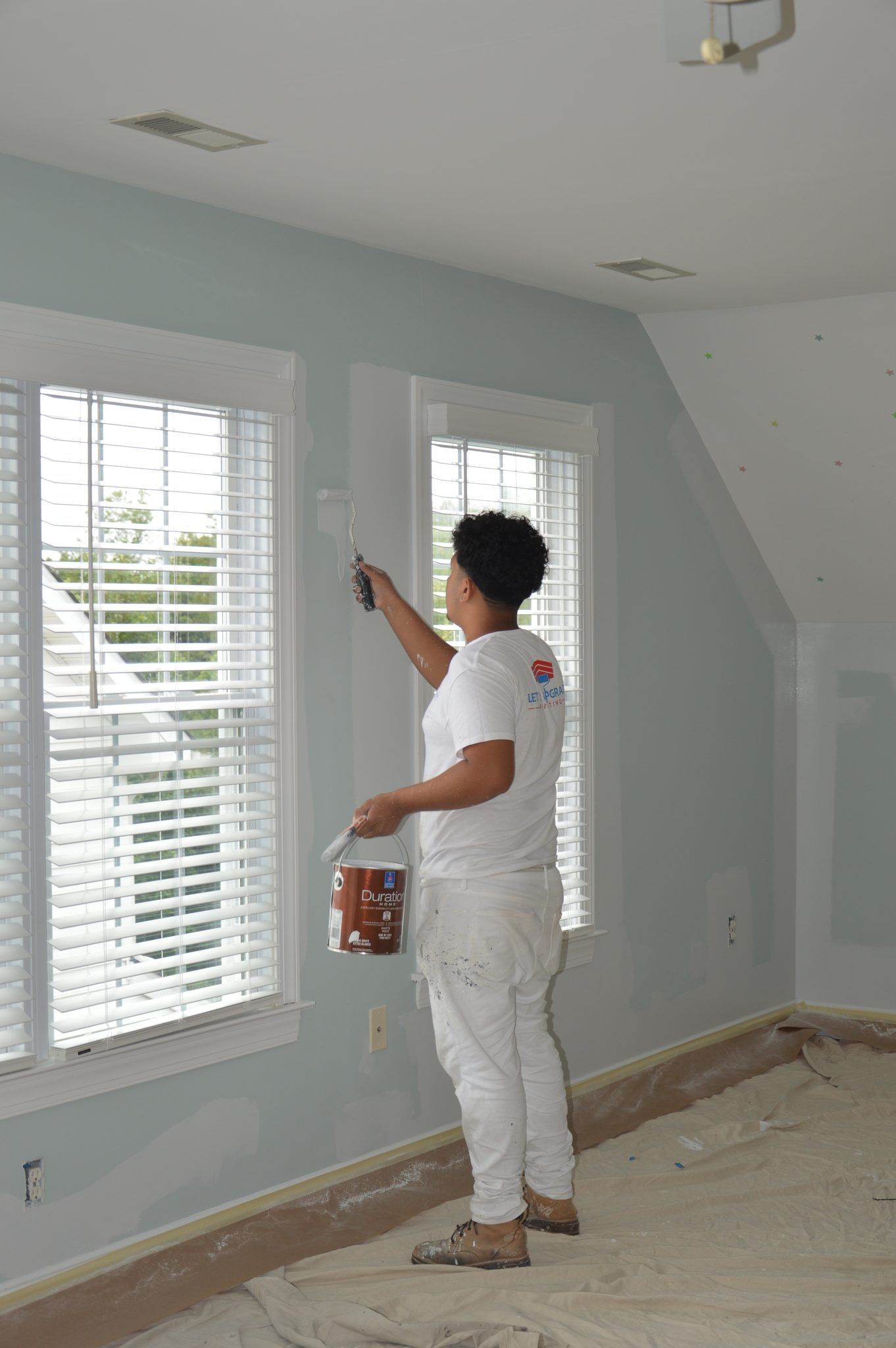 Painter Cutting In Around A Window In A Light Blue Room