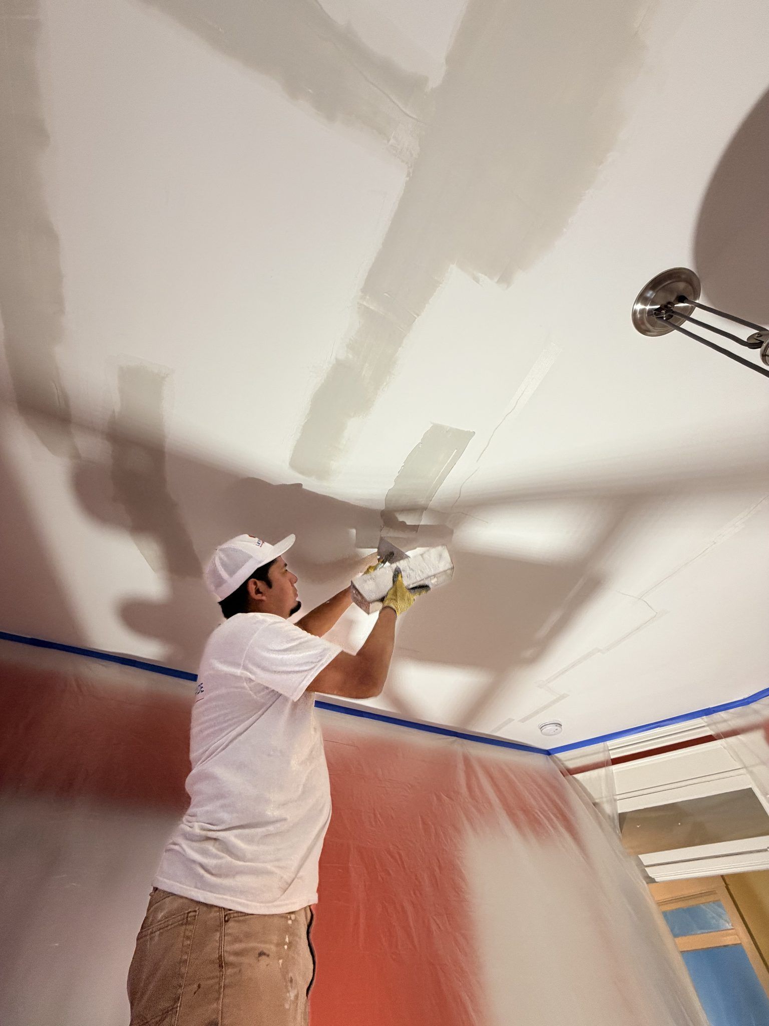 Painter Skim Coating A Ceiling During Drywall Repair