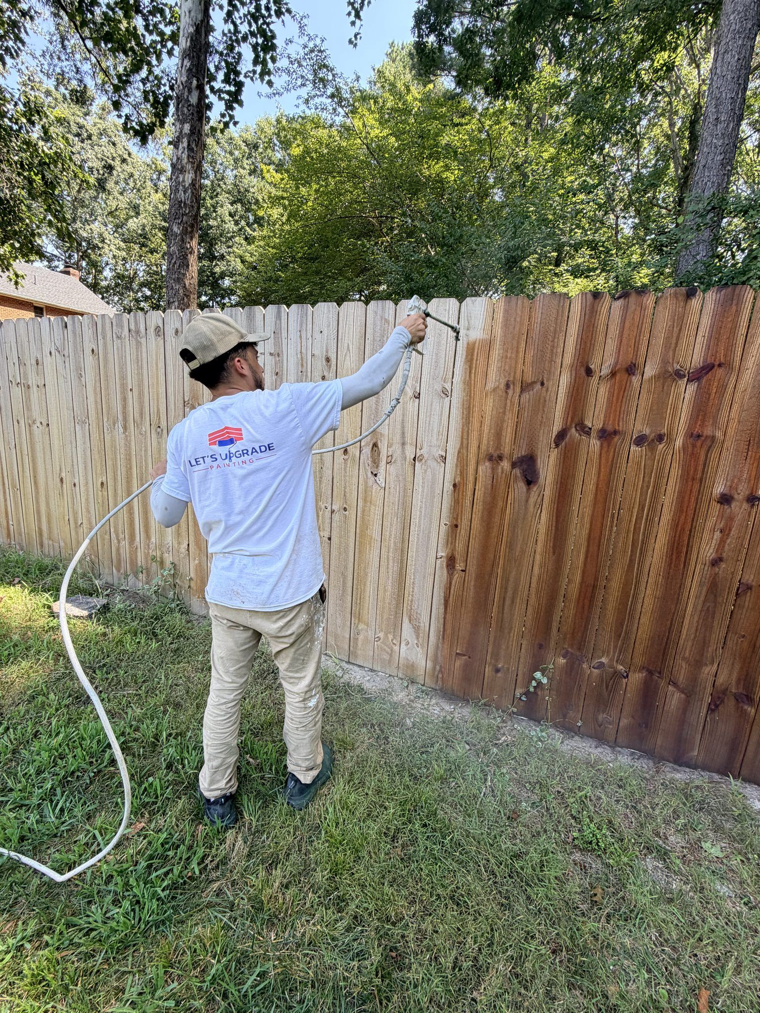 Painter Staining A Wood Privacy Fence