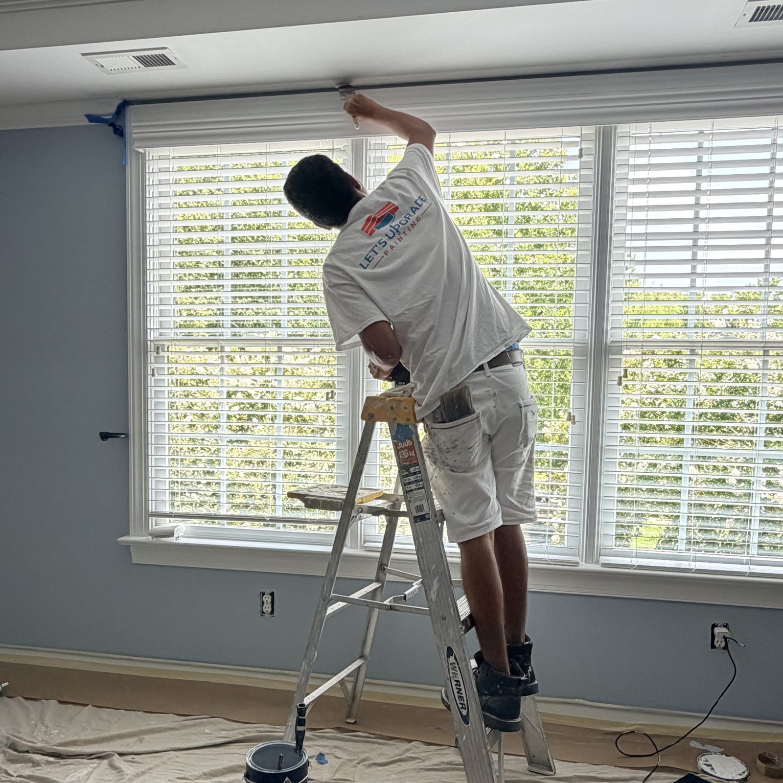 Painter On A Ladder Painting Above A Window
