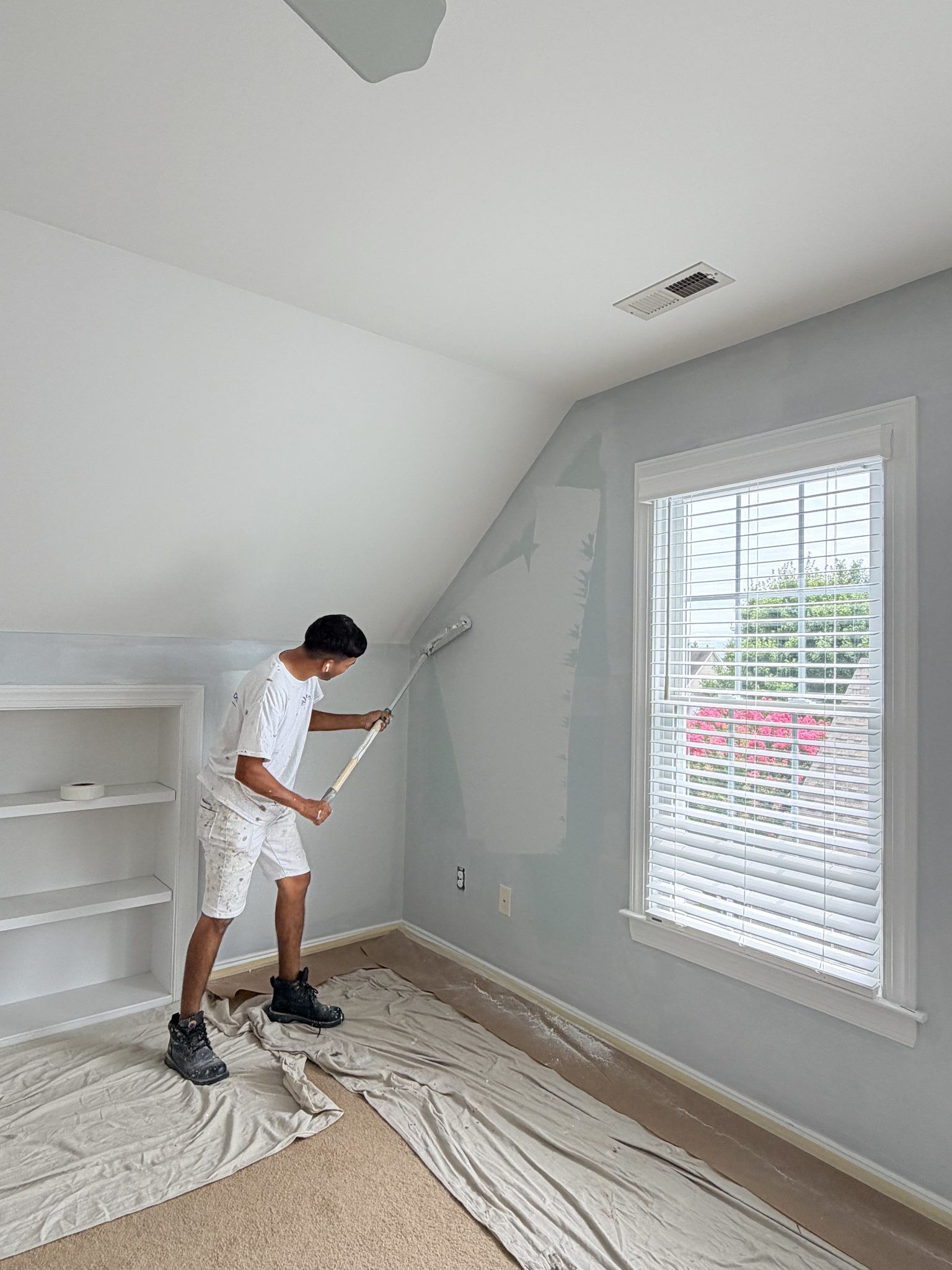 Painter Rolling Walls In An Upstairs Bedroom