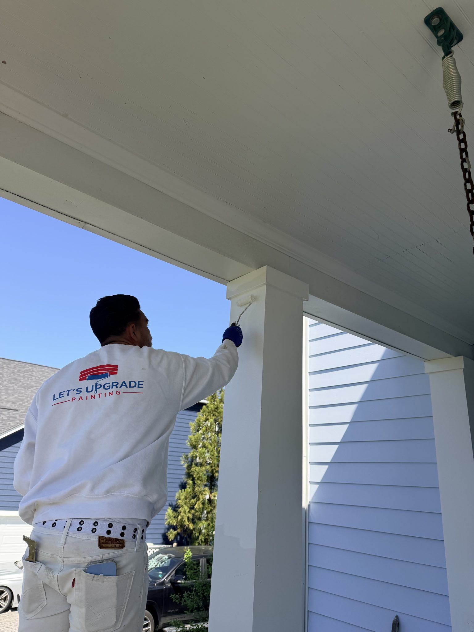 Painter Brushing A White Porch Column