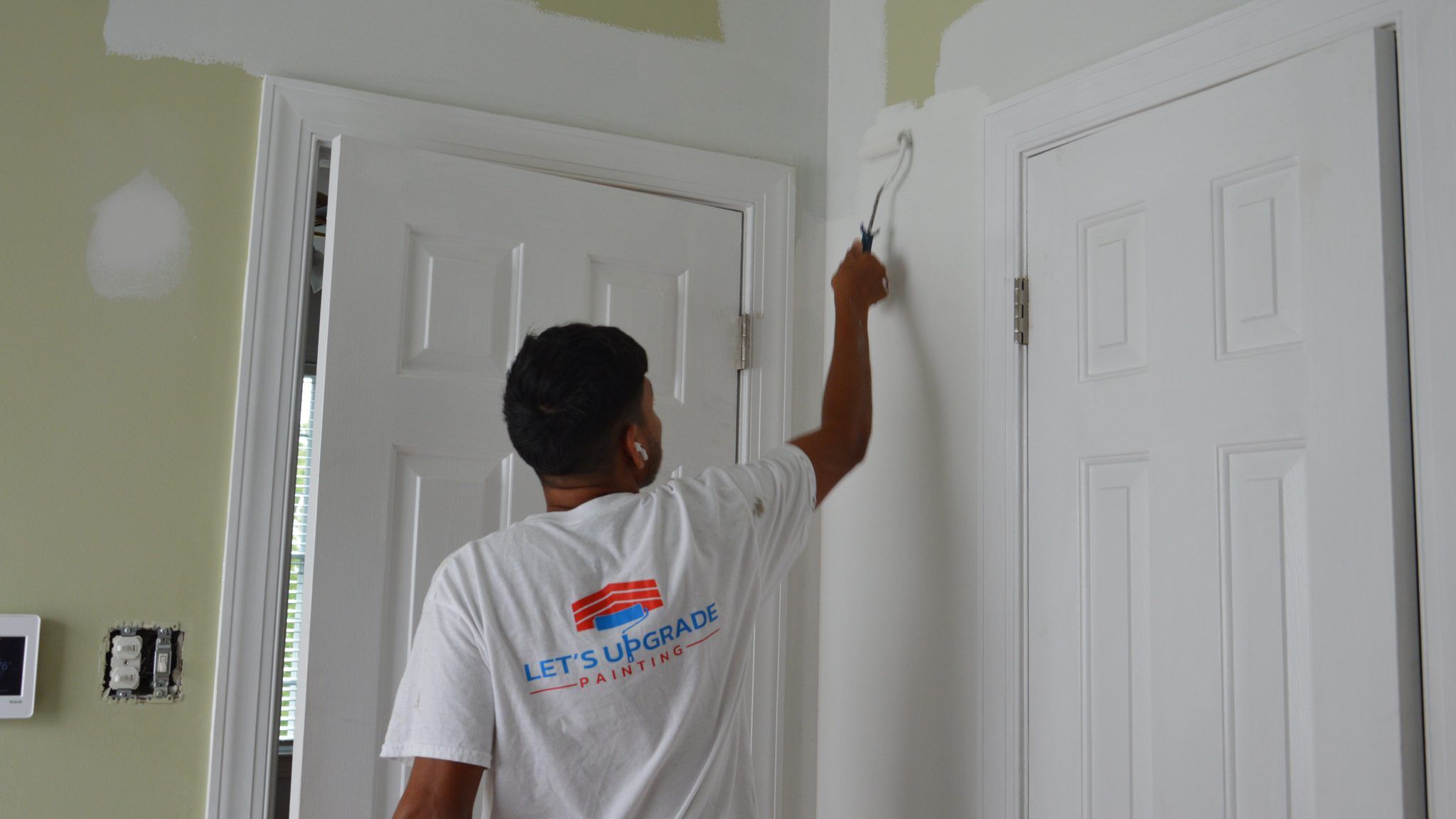 Painter Cutting In White Paint Around Interior Doors