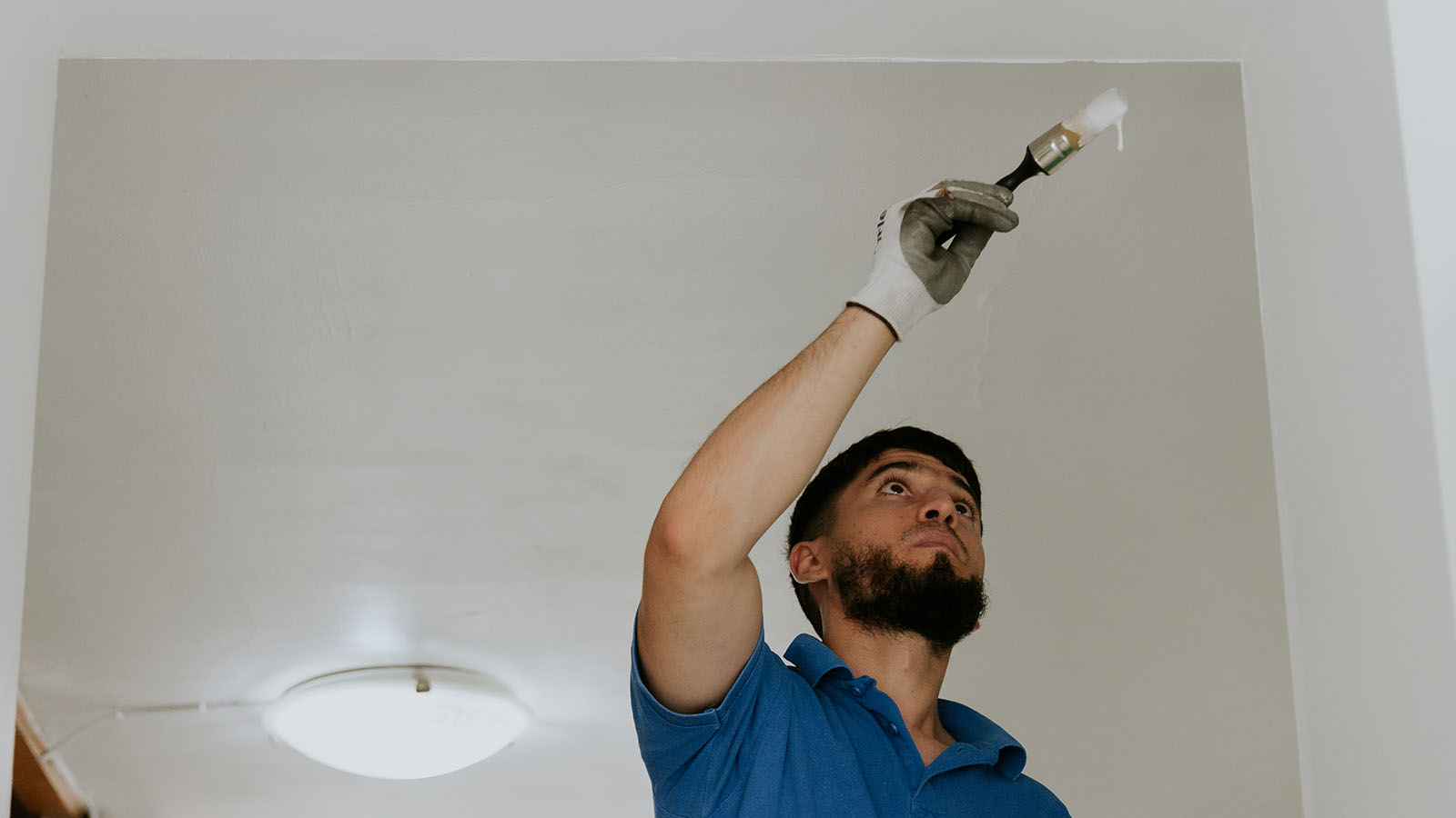 A Young Man Paints The Wall With A Brush