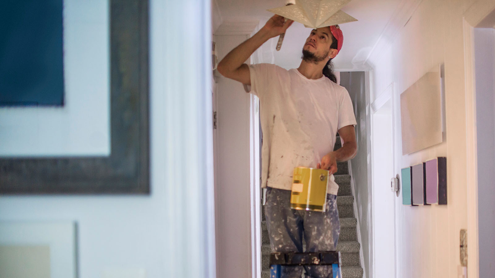 Painter On Step Ladder Cutting In Ceiling With Paint