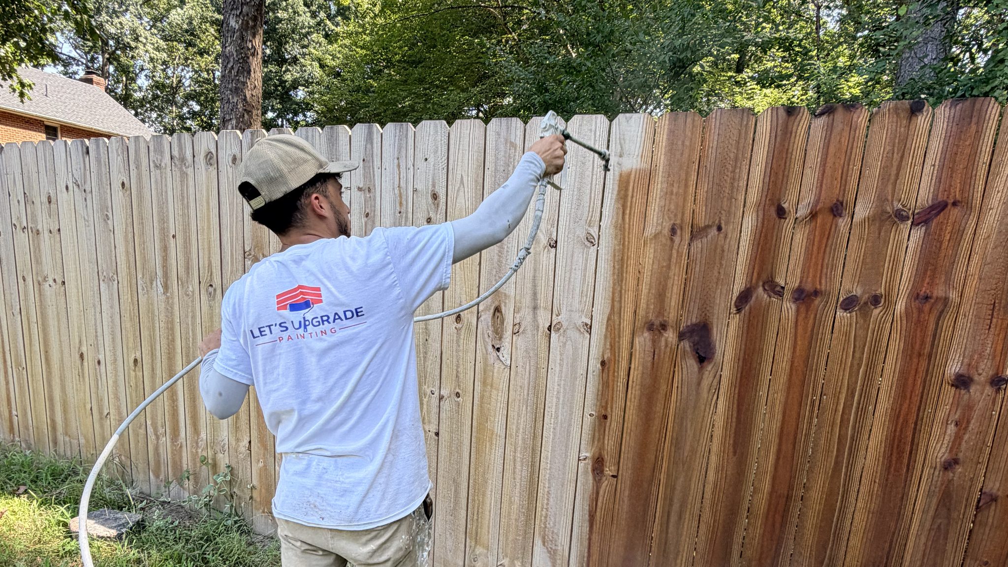 Painter Staining A Wood Privacy Fence