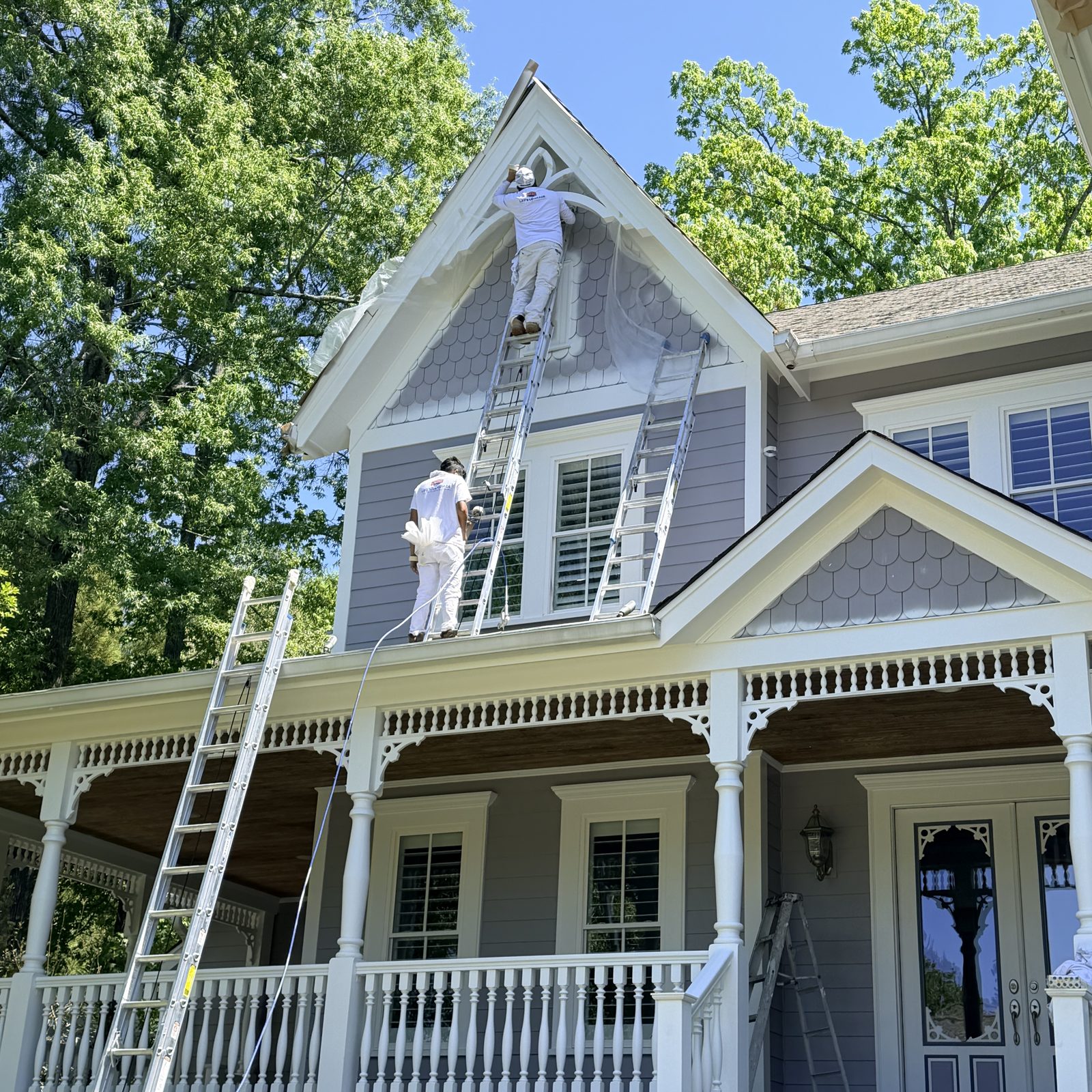 Painters On Ladders Painting A Farmhouse With A Front Porch