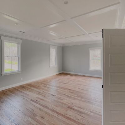 Long View Of A Well-Furnished Room Hall With Forest Green Paint On The Walls, White Ceiling, And Brown Marble Tiling