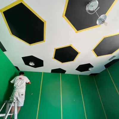 Low-Angle Shot Of A Room In Its Final Painting Touches And A Professional Worker Adding Yellow Lines On The Green Walls