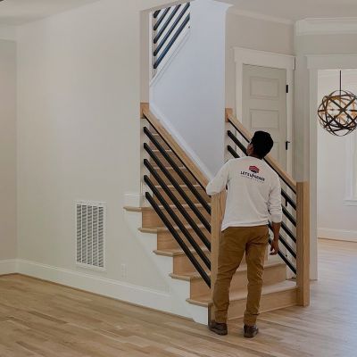 A Painting Professional From Lets Upgrade Painting Company Is Reviewing A Well-Painted House