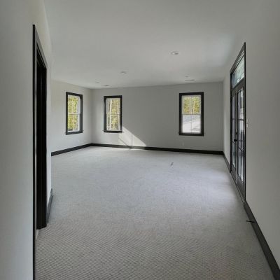 Long View Of The Main Hall With A Grey Carpet On The Floor And Black Borders Drawn On Slider Windows And Doors